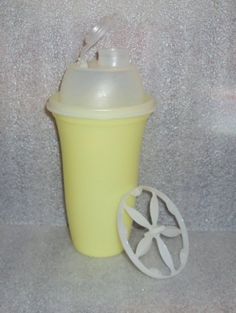 a yellow sippy cup with a straw in it and a white lid sitting next to a plastic object