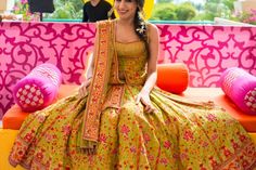 a woman sitting on top of a couch wearing a green dress and yellow shawl