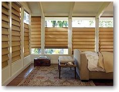 a bed sitting under three windows next to a window covered in shades and blinds on the wall