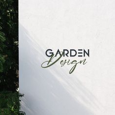 the sign for garden design is next to some green plants and trees in front of it