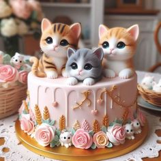 three kittens sitting on top of a cake with pink flowers and gold trimming