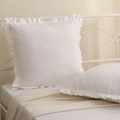 a white bed with two pillows on top of it