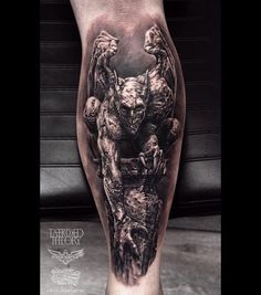 a man's leg with a black and white tattoo on it, depicting an image of a demon