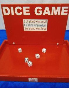 the dice game is on display with its red box and four white dices in it