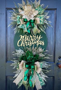 a green and white christmas wreath on a blue door with the words merry christmas written in gold