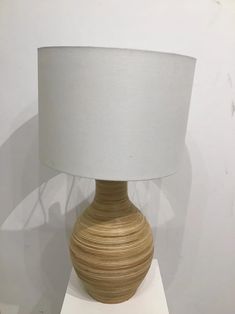 a wooden table lamp with a white shade on it's base and a light bulb in the shape of a vase