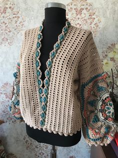 a crocheted shawl is sitting on a mannequin