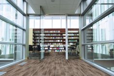 an empty library with lots of bookshelves and glass doors leading to the second floor