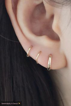 a close up of a person's ear with two small gold hoops on it