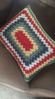 a crocheted pillow sitting on top of a brown couch