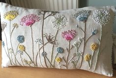 a decorative pillow with flowers on it sitting on a wooden table next to a radiator