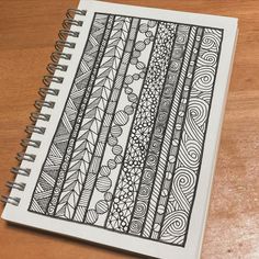 a notebook with an intricate design on the front and back cover, sitting on a wooden table