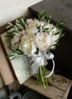 a bouquet of white flowers sitting on top of a wooden table next to an open book