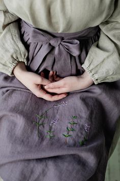 a woman is sitting down with her hands on her stomach and wearing a purple dress