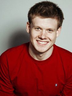 a man in a red shirt smiling at the camera