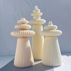 three white vases sitting next to each other on a table