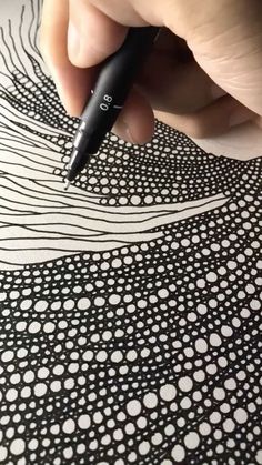 a person is drawing on a piece of paper with a black marker and some white dots