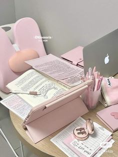 there is a pink desk with an open book and laptop on it