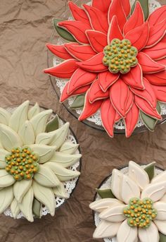 three flower vases sitting on top of a brown cloth covered table next to each other