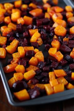 there is a tray full of beets and carrots on the table, ready to be cooked