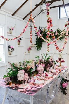 the table is set with pink flowers and plates