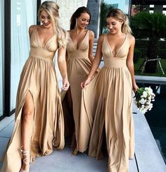 three women in long dresses standing next to each other near a swimming pool and looking at the camera