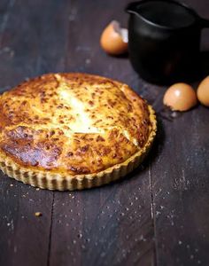 a pie sitting on top of a wooden table next to eggs