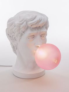 a white bust with a pink bubble coming out of it's mouth and an electric light bulb in front of it