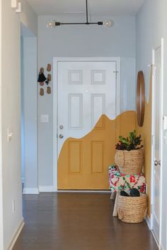 a yellow door and some plants in baskets on the floor next to a white door