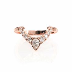 a rose gold ring with two pear shaped diamonds on the front and side, set against a white background