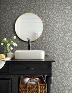 a bathroom with a sink, mirror and basket on the counter top in front of it