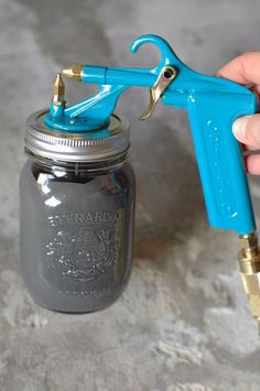 a mason jar with a blue sprayer attached to it and a gold spigot