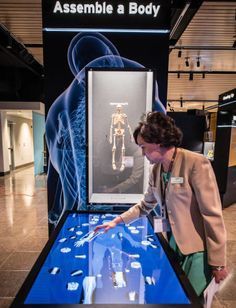 a woman looking at a display case with an image of a human skeleton on it