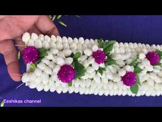 someone is making flowers out of white and purple beads