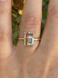 a woman's hand with a ring on it and an emerald stone in the middle