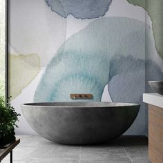 a bathtub in the middle of a bathroom with an artistic wallpaper behind it