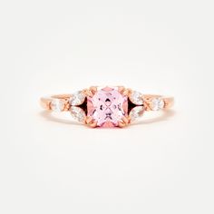 Custom designed by Amelie, and exclusive to Identity Diamonds Recycled metal Set in the center with a lovely 1.25ct* (6mm) cushion cut lab-grown rosé sapphire With a blush hue reminiscent of the color of morganite, our rosé sapphire features a slightly more saturated pink, and it offers a much better durability than morganite, making it ideal for an engagement ring! Available in two different tones: a hint of peach, or a hint of lavender in it Features six marquise shaped lab-grown diamonds, for Rose Gold Cushion Cut Ring With Accent Stones, Rose Gold Square Cut Promise Ring, Rose Gold Rings With Asscher Cut And Accent Stones, Luxury Rose Gold Square Cut Ring, Rose Gold Square Cut Wedding Rings, Spinel Engagement Rings, Montana Sapphire Engagement, Montana Sapphire Engagement Ring, Engagement Ring Pictures