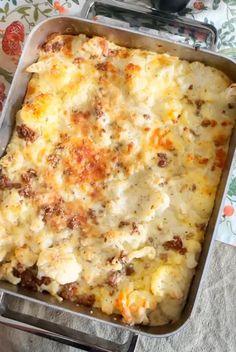 a casserole dish with cheese and meat in it sitting on a tablecloth