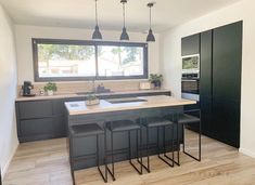 a kitchen with black cabinets and stools next to an island in front of a window