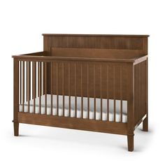 a wooden crib with white sheets on the bottom and side rails, against a white background