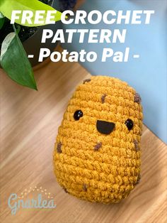 a crochet potato is sitting on a table next to a potted plant