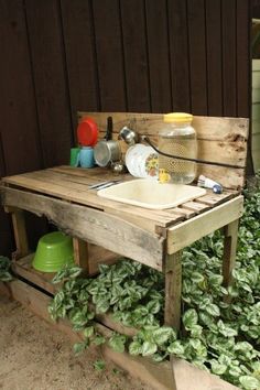 an outdoor sink made out of wooden pallets with plants growing in the back ground