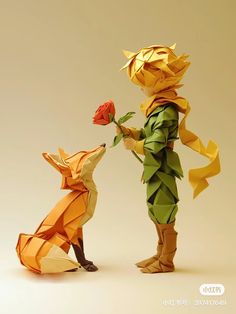 an origami fox with a rose in it's mouth and another animal standing next to it