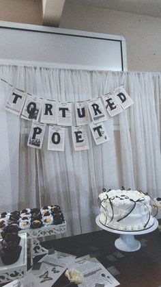 a table topped with cakes and cupcakes next to a banner that says tartured poets