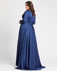 a woman in a long blue dress is looking back at the camera and she has her hands on her hips