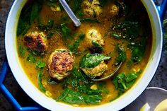 a bowl of soup with meatballs and spinach