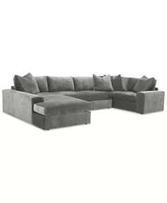 a large gray sectional couch with pillows on the top and bottom corner, in front of a white background