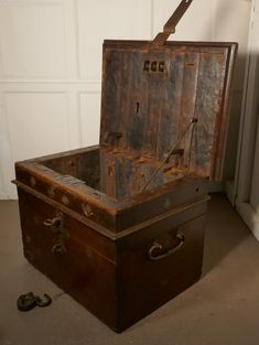 an old wooden trunk sitting on the floor in front of a white wall and door