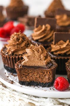 chocolate cupcakes on a white plate with raspberries and other dessert items