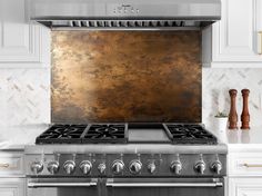 a stove top oven sitting inside of a kitchen next to white cupboards and counter tops